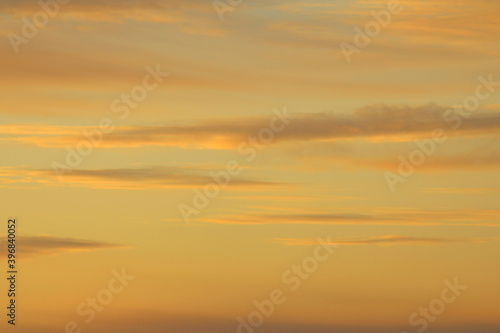 Sun below the horizon and clouds in the fiery dramatic orange sky at sunset or dawn backlit by the sun. Place for text and design.