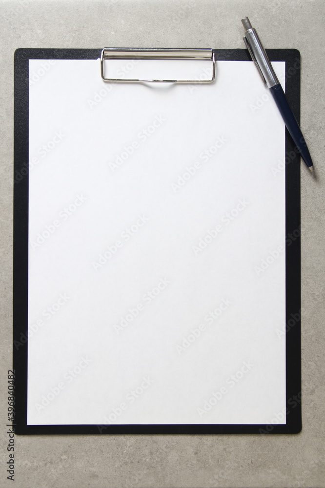 Template of white paper with a ballpoint pen on light grey concrete background in a black tablet with a clip. Concept of new idea, business plan and strategy, development and implementation of content Template of white paper with a ballpoint pen on light grey concrete background in a black tablet with a clip. Concept of new idea, business plan and strategy, development and implementation of content
