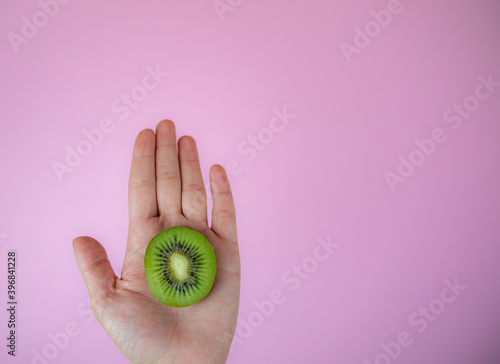 hand with kiwi on the pink background