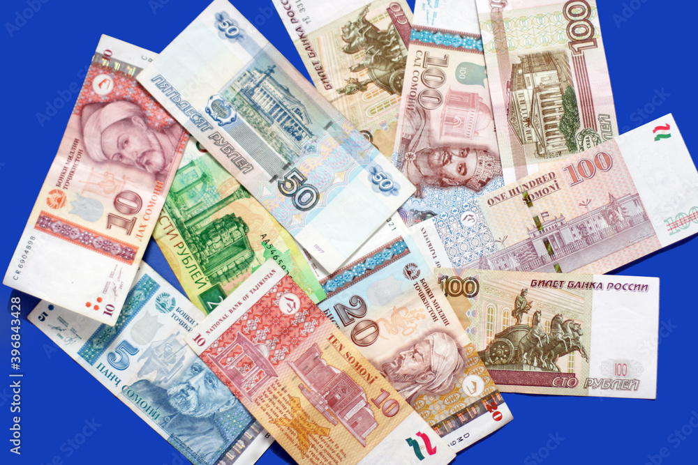 Photo of somoni bank notes from Tajikistan and Russian ruble bank notes on blue background. Photo of somoni bank notes from Tajikistan and Russian ruble bank notes on blue background.