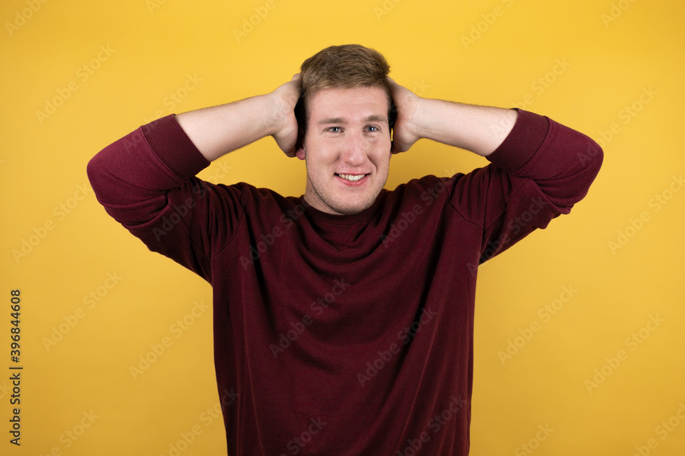 Young blonde man wearing a casual red sweater over yellow background suffering from headache desperate and stressed because pain and migraine with her hands on head Young blonde man wearing a casual red sweater over yellow background suffering from headache desperate and stressed because pain and migraine with her hands on head