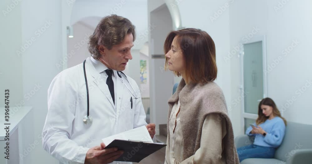 Close up portrait of Caucasian male doctor standing in hospital and speaking with pretty woman patient about treatment results. Healthcare concept. Medical center. Physician concept Close up portrait of Caucasian male doctor standing in hospital and speaking with pretty woman patient about treatment results. Healthcare concept. Medical center. Physician concept