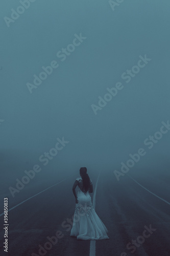 Woman Young Beautiful Lady Walking In Middle Of The Kenyan Highway Road On A foggy misty day in the morning at the Kiambu Limuru Highway Kiambu County Kenya East Africa photo