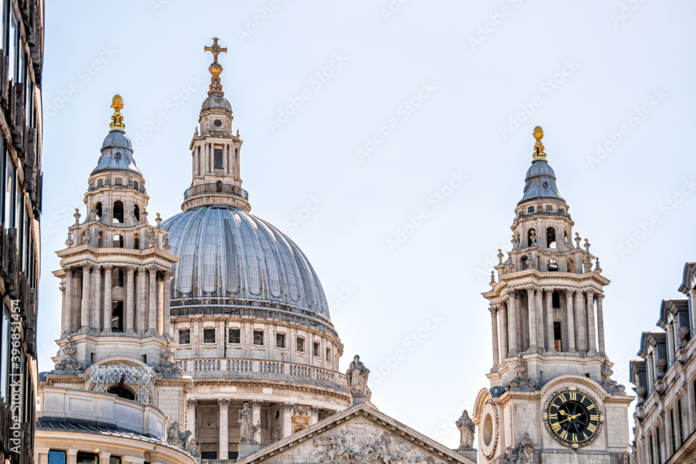 London, UK famous Saint St Paul's Cathedral closeup of dome exterior architecture and blue sky in downtown city and clock cross