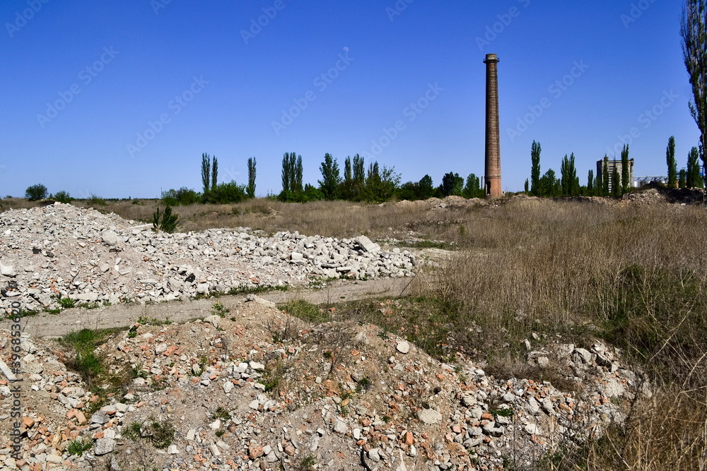Ruins of an abandoned demolished old plant with high rise chimney. Ruined factory in  Ukraine