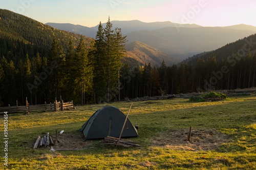 Hiking tent on the background of autumn spruce forest and mountain range where sun comes down  Carpathian mountains  Ukraine