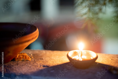 Panning shot of diya oil lamp casting light on a earthenware bird water feeder placed near plants on the hindu festival of diwali