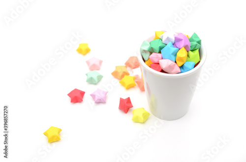 Colorful origami lucky stars spilling out of cup