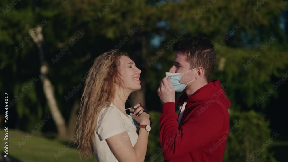 Young man and woman take off medical mask and kiss. Pandemic is over. Finally end of quarantine. Pretty couple date after long self isolation. Health care and medical concept. Happy people. Young man and woman take off medical mask and kiss. Pandemic is over. Finally end of quarantine. Pretty couple date after long self isolation. Health care and medical concept. Happy people.