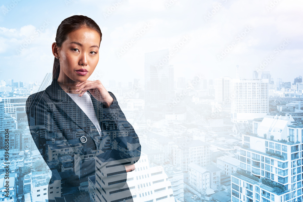 Attractive young Asian business woman in suit with hand on chin thinking how to succeed, new career opportunities, MBA. Bangkok on background. Double exposure. Attractive young Asian business woman in suit with hand on chin thinking how to succeed, new career opportunities, MBA. Bangkok on background. Double exposure.