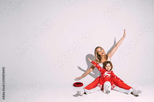 Christmas concept photo of excited young lady and little girl sitting on floor and spreading their arms. Copy space © Вячеслав Косько