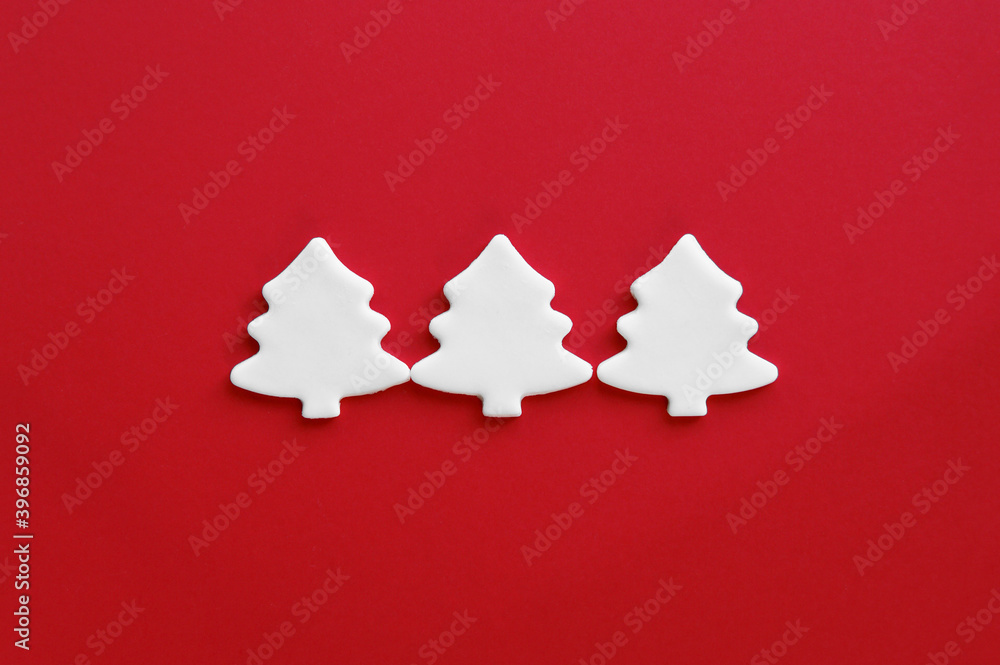 White carved christmas trees of mastic on red background. White carved christmas trees of mastic on red background.