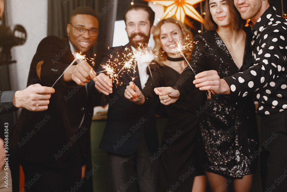 Fototapeta premium People in a Christman decorations. Man in a black suit. Group celebrations New Year. People with bengal lights.