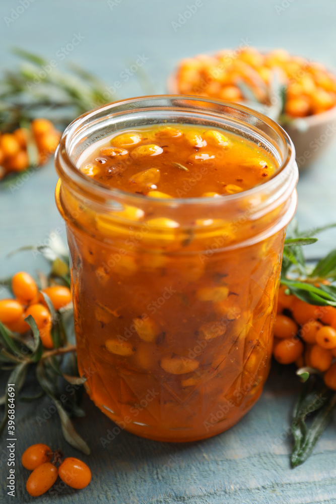 Delicious sea buckthorn jam and fresh berries on blue wooden table Delicious sea buckthorn jam and fresh berries on blue wooden table