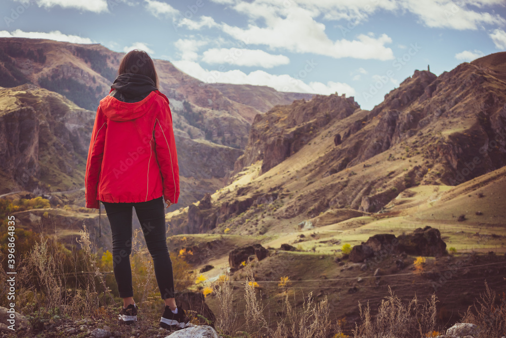 Naklejka premium Woman stands on the edge and admires dramaic landsacape of caucasus in Vardzia. Georgia. Solo freedom and travel blogging.