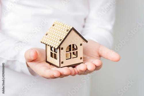 Children's hands hold a wooden house. Family home. International day of families, foster home care, social distancing and home insurance concept.