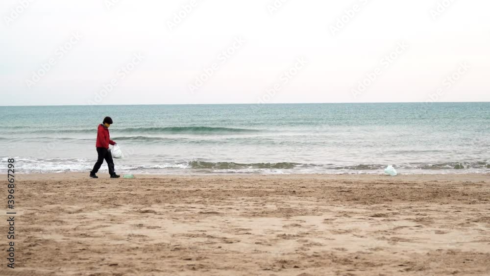 Authentic shot of volunteer woman collecting plastic waste from the beach during coronavirus outbreak - Pollution ocean concept Authentic shot of volunteer woman collecting plastic waste from the beach during coronavirus outbreak - Pollution ocean concept