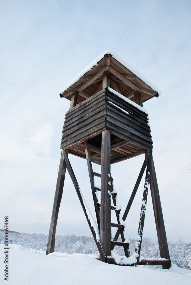 Wooden hunting tower in forest in winter snowy time Wooden hunting tower in forest in winter snowy time