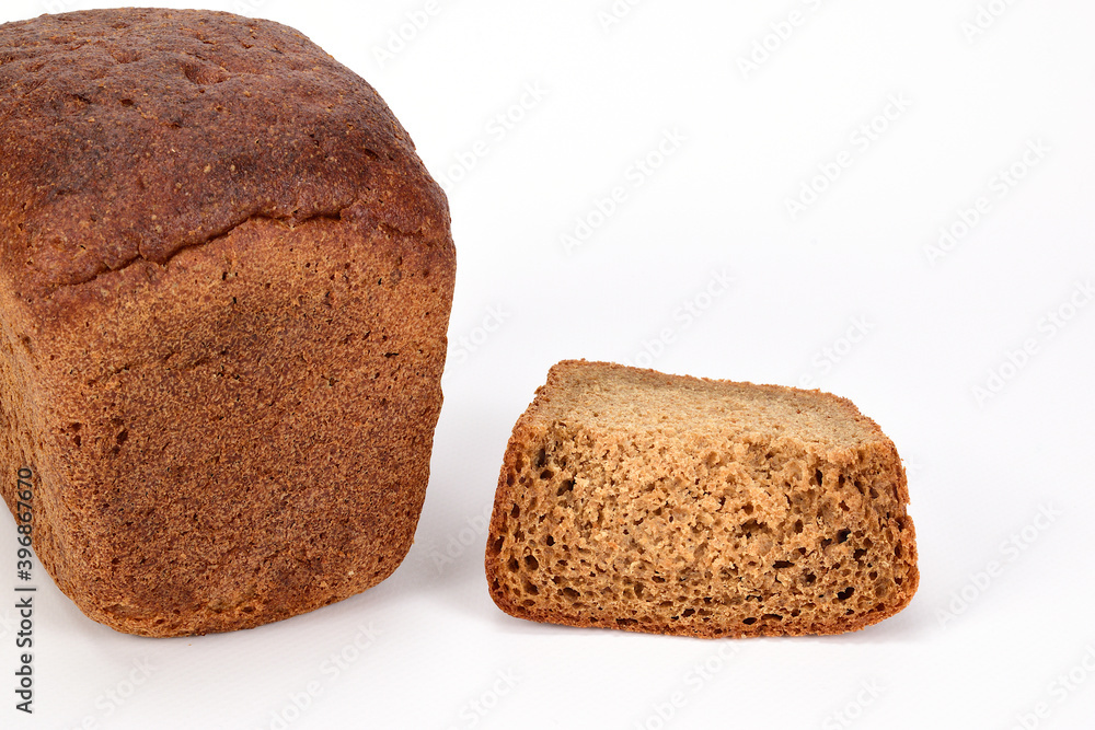 A loaf of homemade black bread next to a cut slice isolated on a white background. A loaf of homemade black bread next to a cut slice isolated on a white background.