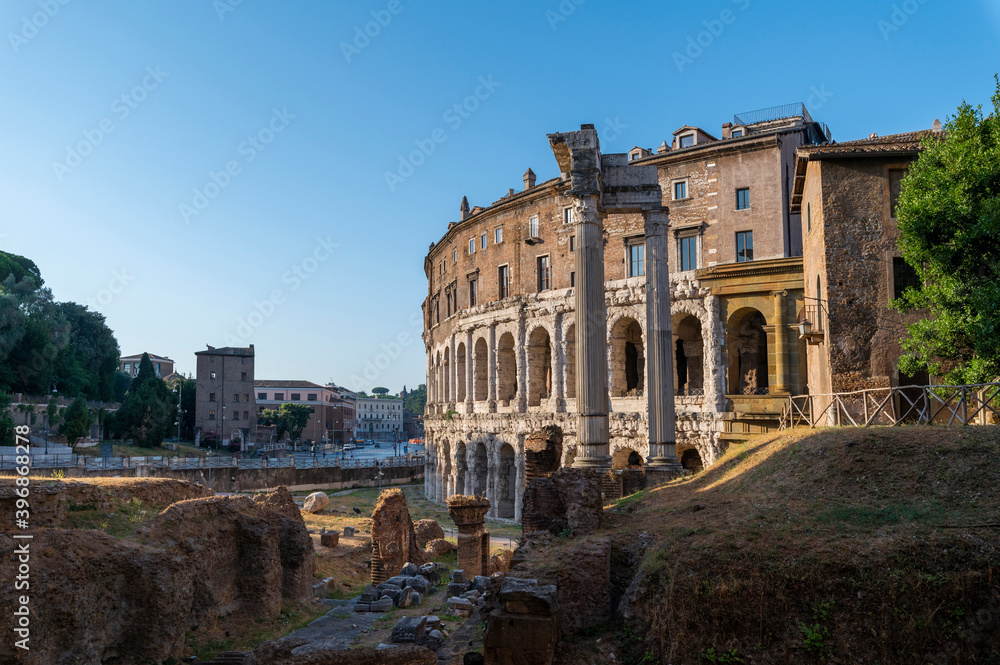 View of the Teatro di Marcello, with the remains of the temple of Apollo Sosiano between the Tiber river and the Capitoline Hill seen from the Jewish quarter, on a sunny day blue sky, clouds. Rome