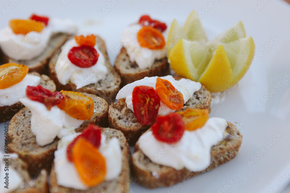 closeup of white platter with red and orange roasted cherry tomatoes on bread with mozzarella closeup of white platter with red and orange roasted cherry tomatoes on bread with mozzarella