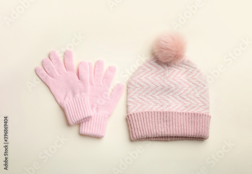 Woolen gloves and hat on beige background, flat lay