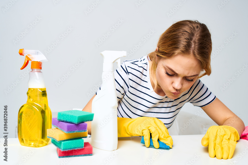 A cleaning lady sits at a table providing housekeeping services light background A cleaning lady sits at a table providing housekeeping services light background
