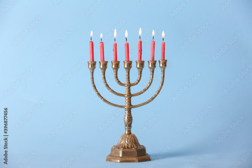 Fototapeta premium Golden menorah with burning candles on light blue background