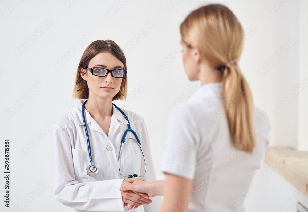 doctor in a medical gown with a stethoscope and a patient in a white t-shirt back view doctor in a medical gown with a stethoscope and a patient in a white t-shirt back view