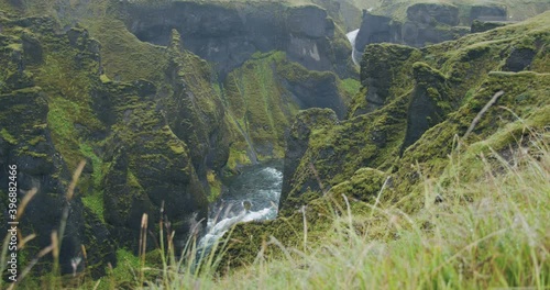 Fjadrargljufur canyon. Bizarre steep cliff rock formations and winding river in the valley with defocused foliage in foreground. Iceland, Europe photo