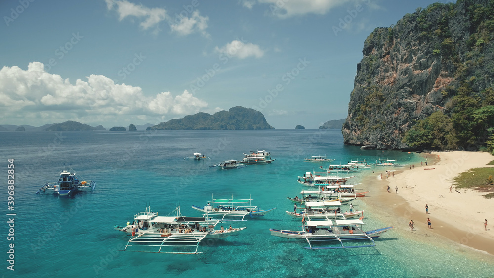 Aerial view of passenger boats with tourists rest at sea sand beach of Palawan island, Philippines, Visayas Archipelago. Tropic nature highlands landscape with green forest at summer day