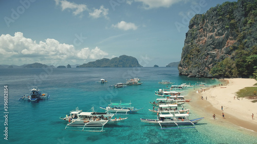 Aerial view of passenger boats with tourists rest at sea sand beach of Palawan island, Philippines, Visayas Archipelago. Tropic nature highlands landscape with green forest at summer day