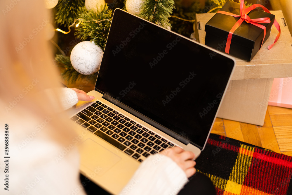 Photo of a beautiful blond female sitting on a couch using a laptop to shop for Christmas gifts. Photo of a beautiful blond female sitting on a couch using a laptop to shop for Christmas gifts.