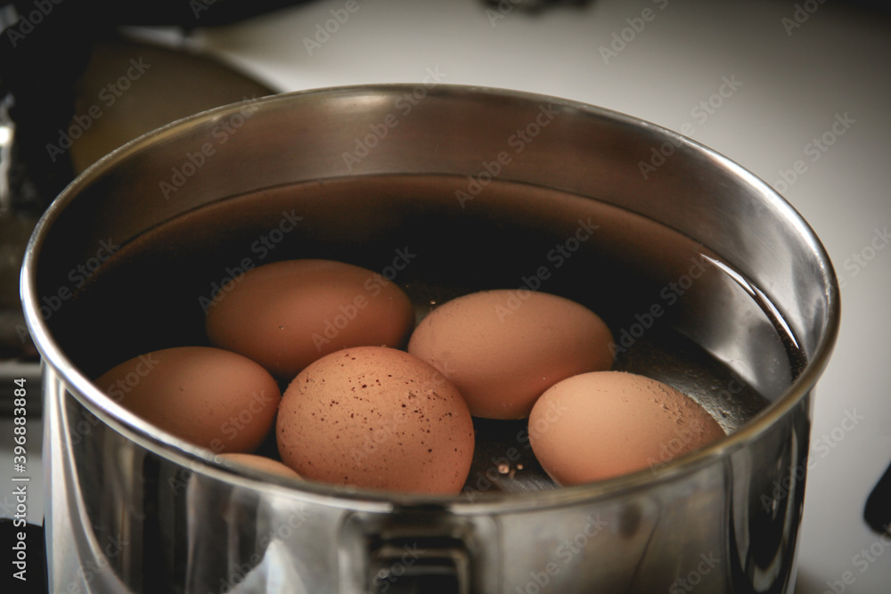 Brown eggs boiling in a small pot on the stove Brown eggs boiling in a small pot on the stove