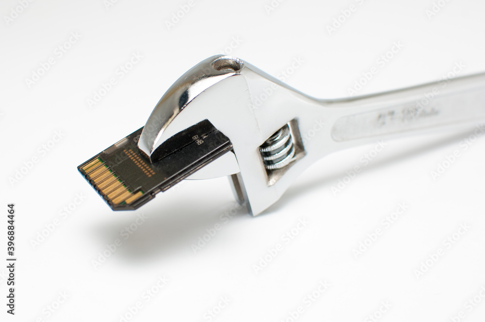 Monkey wrench and SD memory card on white background Monkey wrench and SD memory card on white background