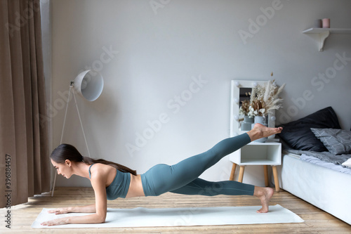 Fit woman doing yoga plank  training in living room.