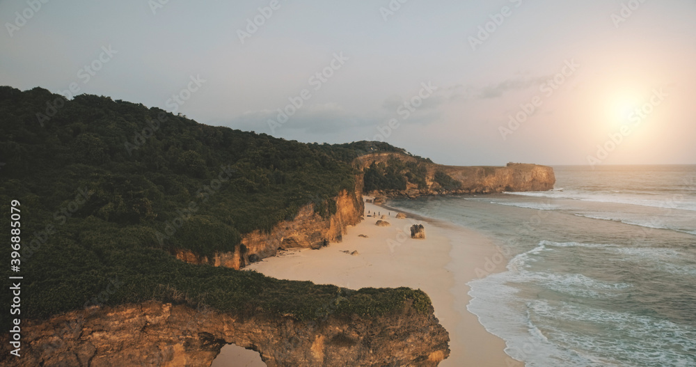 Tourist attraction closeup aerial: cliff wall of Batu Bolong, Bawana Beach, Sumba Island, Indonesia. Unique geological formation with green grass on top. Indonesian cinematic soft light drone shot