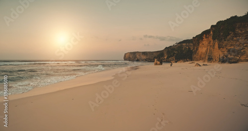 Aerial sunny sand beach at ocean wavy bay. Nobody nature seascape with sandy sea coast and rocks. Sun disk over waves at summer morning. Epic sunrise at tropic Sumba island, Indonesia, Asia © Goinyk