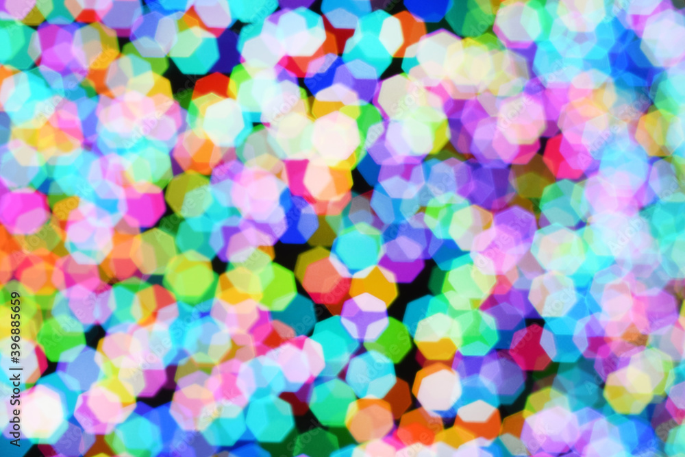 Christmas background, garland in blur. Glowing and festive colored light circles created in camera and bokeh lens. Christmas fairy lights are defocused giving a blurry effect.