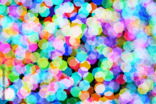 Christmas background, garland in blur. Glowing and festive colored light circles created in camera and bokeh lens. Christmas fairy lights are defocused giving a blurry effect.
