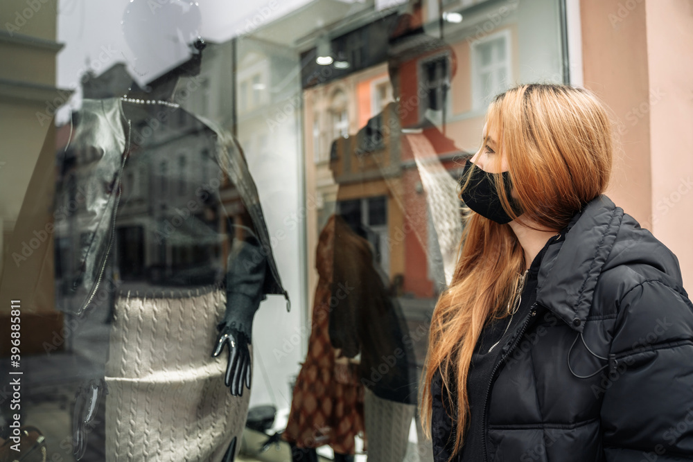 Woman looks at mannequin in shop window. Girl customer near store. Black Friday. Female shopping