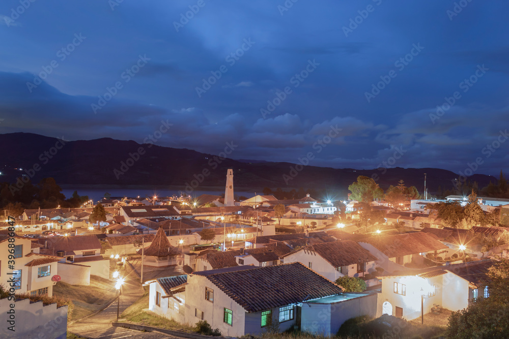 Guatavita Colombian colonial town at evening blue hour with city lights and tominé lake at background. Travel and architecture concept 