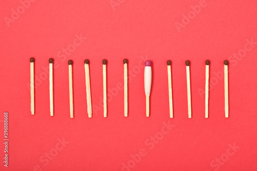 matches are arranged in a row on a red background, one waterproof match among simple matches