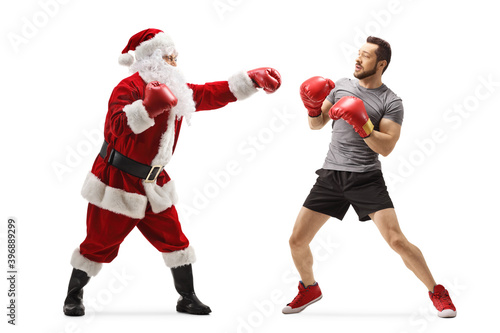 Full length profile shot of a boxer and santa claus fighting with boxing gloves