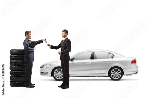 Full length profile shot of a mechanic in a uniform returning car keys to a businessman with a silver car © Ljupco Smokovski
