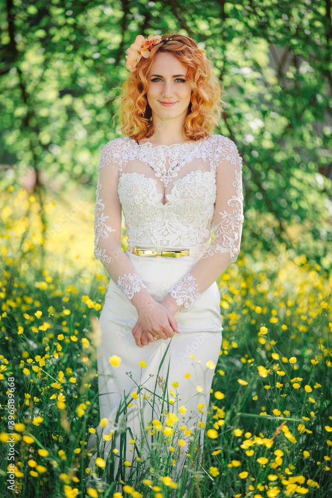 Beautiful redhead Bride in stylish wedding dress in blooming spring garden. Attractive red-haired girl in a white lace dress walks in a green park. Beautiful redhead Bride in stylish wedding dress in blooming spring garden. Attractive red-haired girl in a white lace dress walks in a green park.