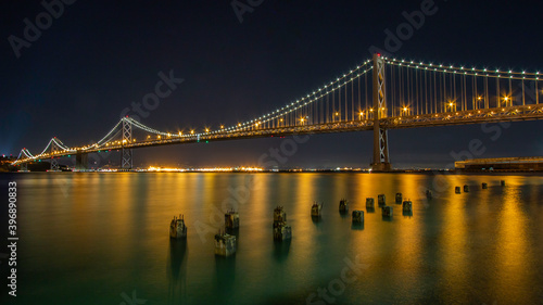 Night image of the Oakland Bridge as it leaves San Francisco and heads northwest into Oakland with lighted reflections of sunken pier ballasts © Jeffery Edwards
