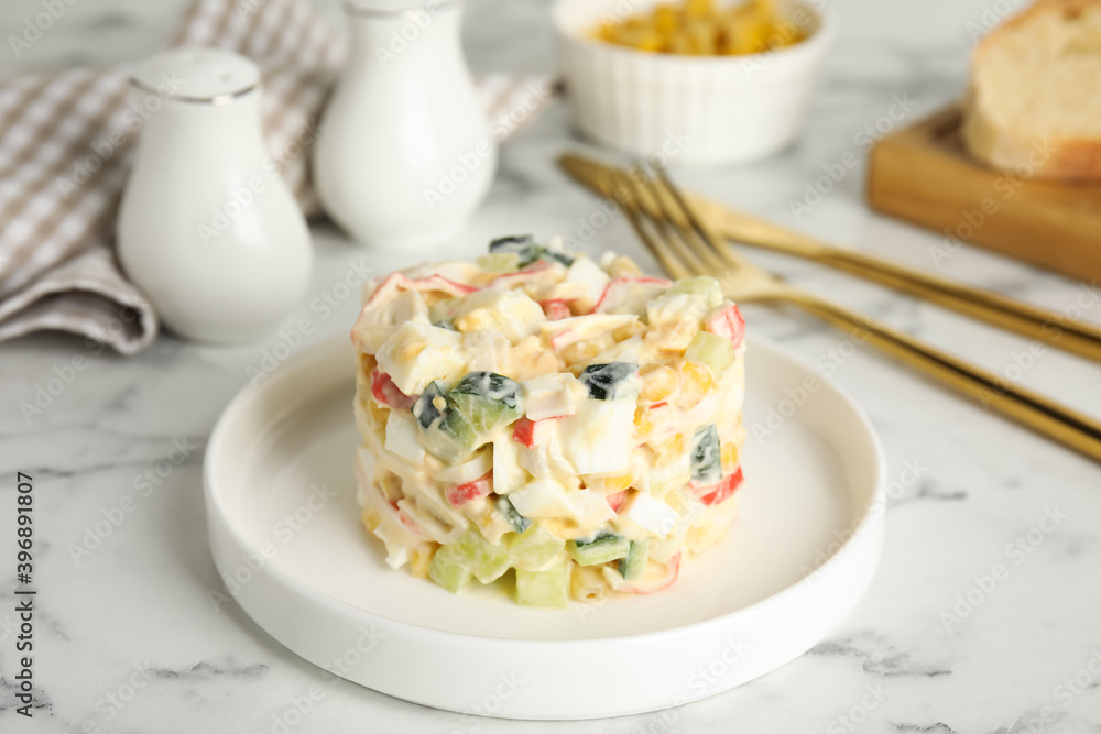 Delicious salad with fresh crab sticks on white marble table