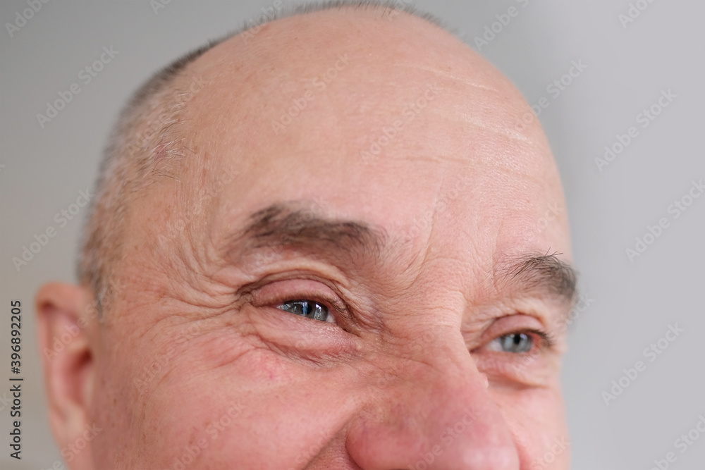 close-up and front view of the gray eye of an old caucasian man in his sixties, with strong wrinkles, bright emotions on his face, male skin care concept close-up and front view of the gray eye of an old caucasian man in his sixties, with strong wrinkles, bright emotions on his face, male skin care concept