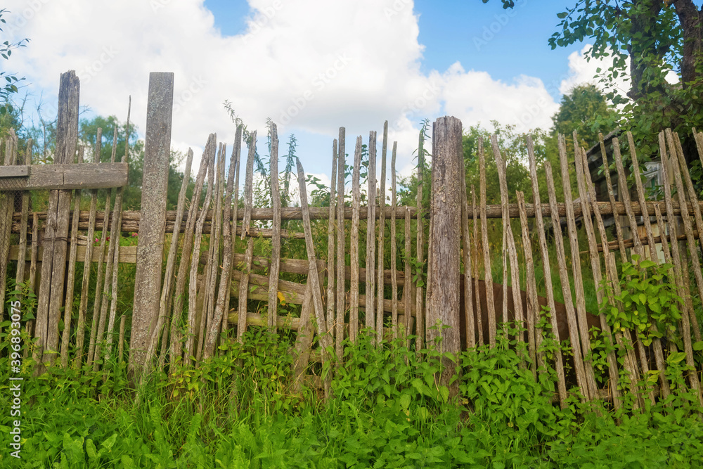 Old rickety wooden fence made of narrow boards in front of village house Old rickety wooden fence made of narrow boards in front of village house